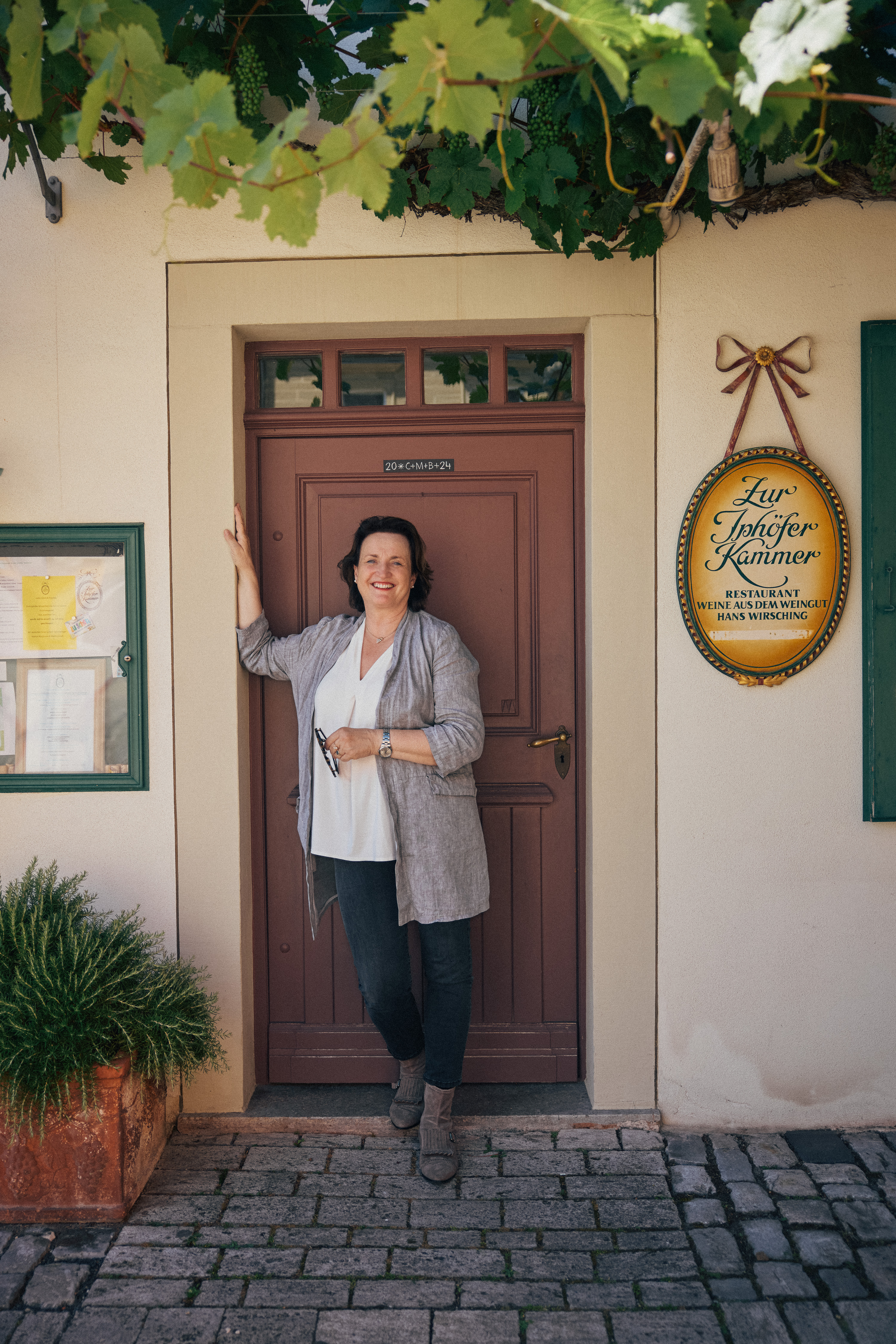 Andrea Wirsching an der Vinothek-Tür unter dem Rebdach